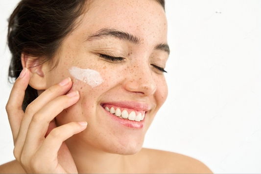 Femme appliquant de la crème solaire sur son visage pour protéger sa peau à tendance acnéique des rayons UV